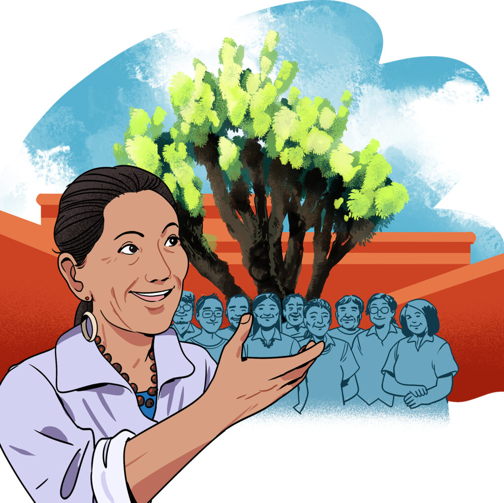 Former United States Secretary of the Interior Deb Haaland stands in front of a crowd gathered underneath a tall joshua tree.