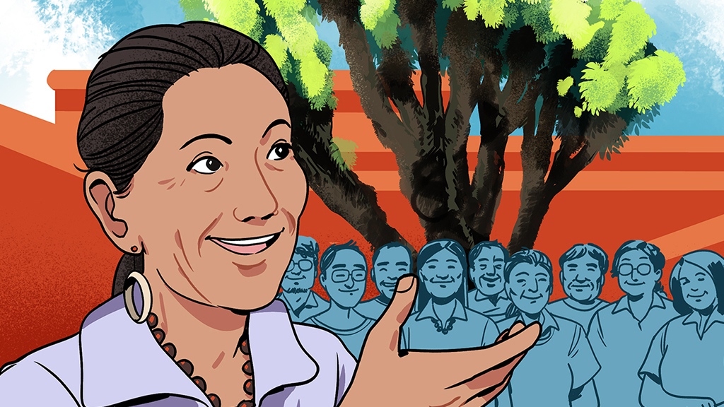 Former United States Secretary of the Interior Deb Haaland stands in front of a crowd gathered underneath a tall joshua tree.